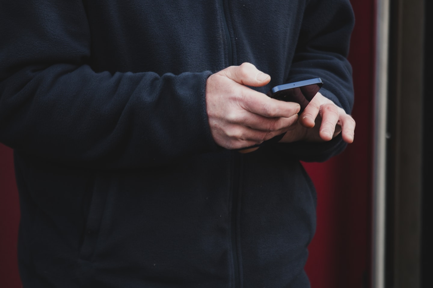 Eine Person hält ein Smartphone in einer Hand und bedient es mit der anderen.